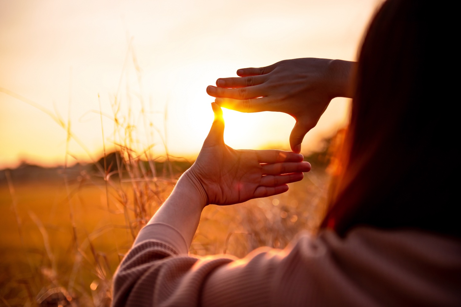 hands framing the sun